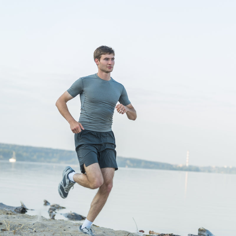 Man running on a beach with water and sky in the background