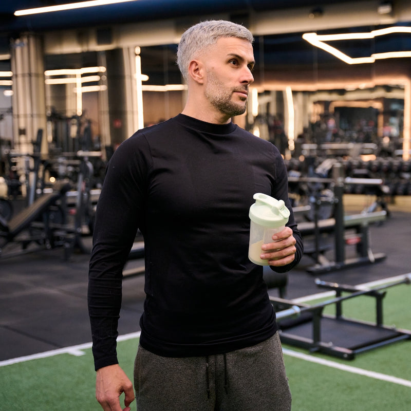 Man holding a protein shake in a gym setting