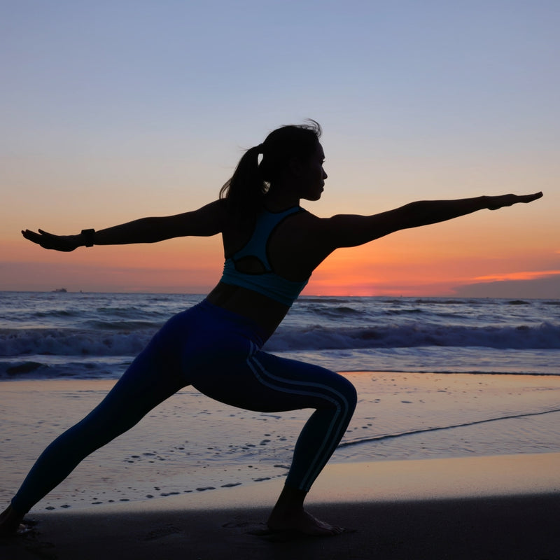 Person practicing yoga on a beach at sunset